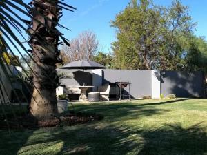 a house with a table and an umbrella in a yard at 5@Partridge Guesthouse in Newcastle