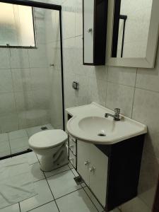 a white bathroom with a toilet and a sink at Avenida Plaza Hotel in Pindamonhangaba
