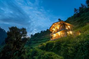 a house on the side of a hill at night at Perfect Home for Stay in Jibhi