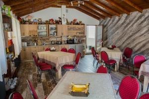 a kitchen and dining room with tables and red chairs at Casa Majestic in Călimăneşti