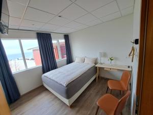 a bedroom with a bed and a desk and a window at The Old Post Office Guesthouse in Grundarfjordur +37 photos