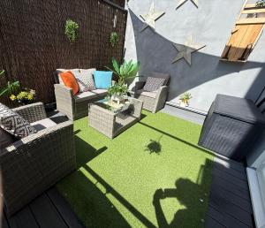 a small backyard with a patio with chairs and grass at The Duplex with Air Conditioning & Private Deck Area in Margate