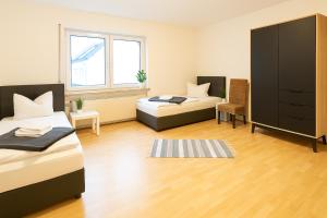 a bedroom with two beds and a cabinet and a chair at SUNNYHOME Monteurwohnungen und Apartments in Schwandorf in Schwandorf in Bayern +3 photos