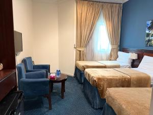 une chambre d'hôtel avec deux lits et une chaise dans l'établissement فندق نما مودة Namma Mawaddah Hotel, à La Mecque