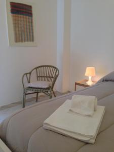 ein Schlafzimmer mit einem Bett mit einem Stuhl und einer Bank in der Unterkunft Pace 27 in Alghero