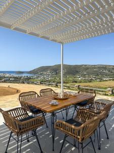 a wooden table with chairs and an umbrella at Vista del Porto Apartment in Gavrio