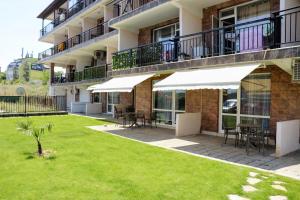 a patio with tables and white umbrellas in front of a building at Апартамент Студио Endless Созопол in Sozopol
