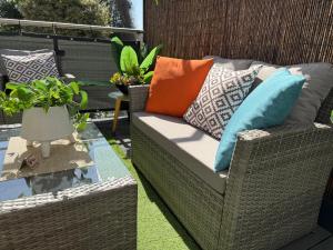 a wicker chair with colorful pillows on a patio at The Duplex with Air Conditioning & Private Deck Area in Margate