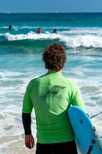 a man walking into the ocean with a surfboard at Villa Stars Seaview Corralejo in Corralejo