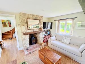 ein Wohnzimmer mit einem Sofa und einem Steinkamin in der Unterkunft Charming modernized country cottage Near Mere, Wiltshire in Mere