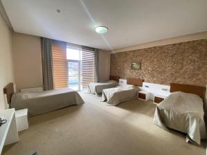 a bedroom with three beds and a large window at Arena Hotel Dashkasan in Xoşbulaq