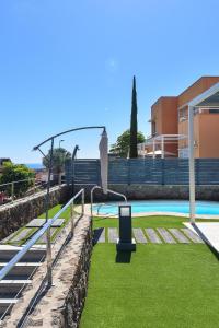 a pool with green grass next to a building at Vista Golf 5 by Villagrancanaria in La Playa de Arguineguín
