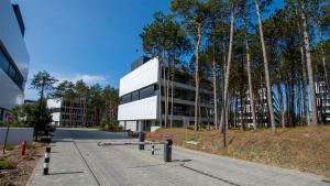 a white building with trees in front of it at VacationClub - Shellter Rogowo Apartament 6 in Rogowo