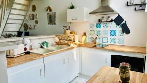 a kitchen with white cabinets and a wooden counter top at Chez Mag maison de pêcheur proche plage in Ault