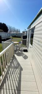 a deck with a table and chairs on a building at 4 Berth Static Caravan Golden Palm Resort with Decking in Chapel Saint Leonards