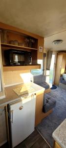 an rv with a kitchen and a living room at 4 Berth Static Caravan Golden Palm Resort with Decking in Chapel Saint Leonards +13 photos