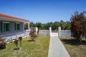 a house with red flowers in the yard at Mariettas Cottage in Pigadhákia