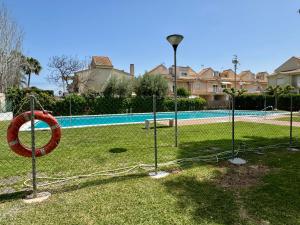 Ein Zaun mit einem roten Ring im Gras neben einem Pool in der Unterkunft Sunset Grao Beach in Grao de Castellón