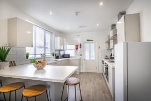 una cocina blanca con una gran isla blanca con taburetes en Teesside House - Sleeps up to 10, en Redcar