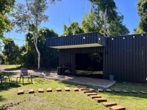 a black building with a bench in a yard at RASTRO Cabins in Restinga Sêca