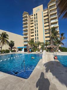 a shadow of a person in a swimming pool in front of a hotel at Espectacular Beach & Laguna view Cancun at SALVIA CONDOMINIUMS in Cancún