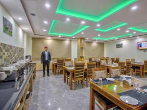 a man standing in a dining room with tables and chairs at Swastik Grand Manali in Manāli +30 photos