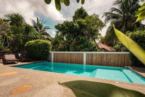 a swimming pool in a yard with a fence and trees at Siyada Villa in Lamai