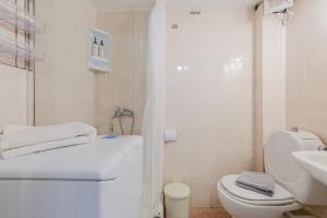 a white bathroom with a toilet and a sink at Hidden Pine in Pefkohori +14 photos