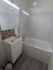 a white bathroom with a tub and a sink at Chez Camille in Dives-sur-Mer