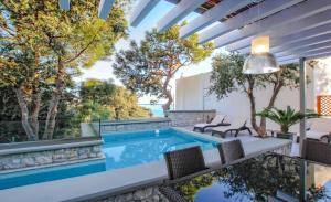 ロードスにあるExecutive Rhodes Villa Villa Barbie 2 Bedroom With Sea Views Pefkosの椅子と景色の見えるパティオを備えた屋内プール