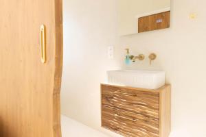 a bathroom with a white sink and a wooden cabinet at Sublime, hyper-centre d'Ajaccio, avec Spa, Sauna, Vue mer & Plage à 3min in Ajaccio