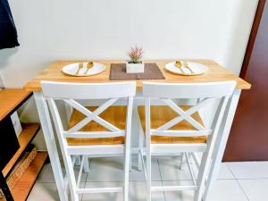 a dining room table with two white stools at Cozy Space at Horizons 101 Cebu City with Pool, Netflix, Wifi in Cebu City +37 photos