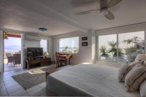 a bedroom with a bed and a tv and windows at Super Luxury Skiathos Villa Seven Stunning Bedroom Suites Villa Daphne Achliades in Achladies