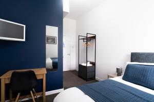 a bedroom with a bed and a desk with a computer at Citysteps Hotels Newcastle West in Newcastle upon Tyne