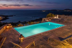 a pool with a view of the ocean at night at Platinum Paros Villa 3 Bedroom Villa Amazing Sea Views & Private Infinity Pool Access Parikia in Parasporos +34 photos