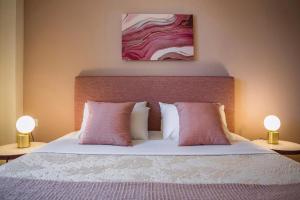 a bedroom with a bed with pink pillows and two lamps at Deluxe Kefalonia Apartment Apartment Perla 1 Bedroom Pool Sea View Karavomilos in Karavomylos +3 photos