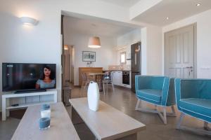 a living room with a television and blue chairs at Platinum Paros Villa 3 Bedroom Villa Amazing Sea Views & Private Infinity Pool Access Parikia in Parasporos