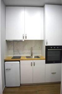 a kitchen with white cabinets and a sink at PLATINUM ApartmentsINNThebeach in Vlorë