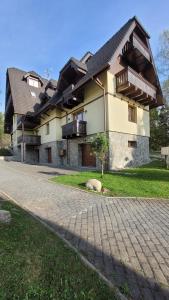 塔查斯卡-鲁穆尼卡Apartmány u tatranky的一栋大房子，前面有一条砖砌车道