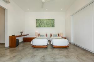 een slaapkamer met 2 bedden, een bureau en een schilderij bij Gajah Villas Bali by Nagisa Bali in Seminyak +65 foto's