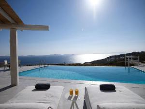 a swimming pool with two beds and a view of the ocean at Exquisite Mykonos Villa Villa Ammos 4 Bedroom Private Pool Sea View Houlakia in Mýkonos City