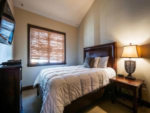 een slaapkamer met een bed, een lamp en een raam bij Fairway Springs by Park City Vacations in Park West Ski Area Heliport