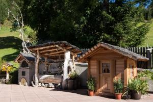 a small wooden house with a tree stump in a yard at Appartamenti Col da Vënt in Corvara in Badia