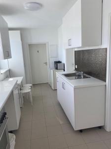 a white kitchen with a sink and white cabinets at GoldStar Apartment-ganze Ferienwohnung Hannover-Sarstedt in Sarstedt +5 photos