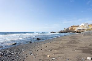 a beach with rocks in the water and buildings at Home2Book Serene Stay & Sea View Terrace in Arico in La Mareta
