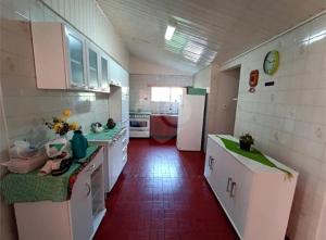 eine Küche mit weißen Schränken und einem roten Boden in der Unterkunft Residência Silva in Itajaí