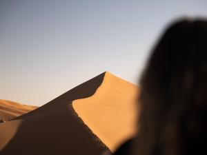 a woman standing in front of a sand dune at Dar Ahmed in Tagounite