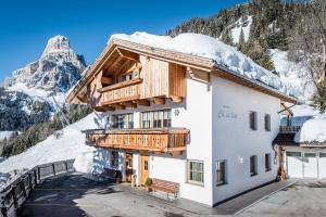 a hotel with snow covered mountains in the background at Appartamenti Col da Vënt in Corvara in Badia