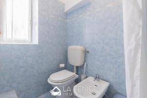 a blue tiled bathroom with a toilet and a window at House by the sea in Riomaggiore +10 photos