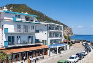 a building on a street next to the ocean at La casa del pescatore in Cala Gonone